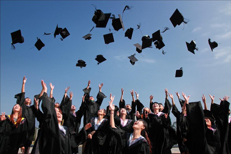 Picture of a graduation celecration with caps being thrown in the air.